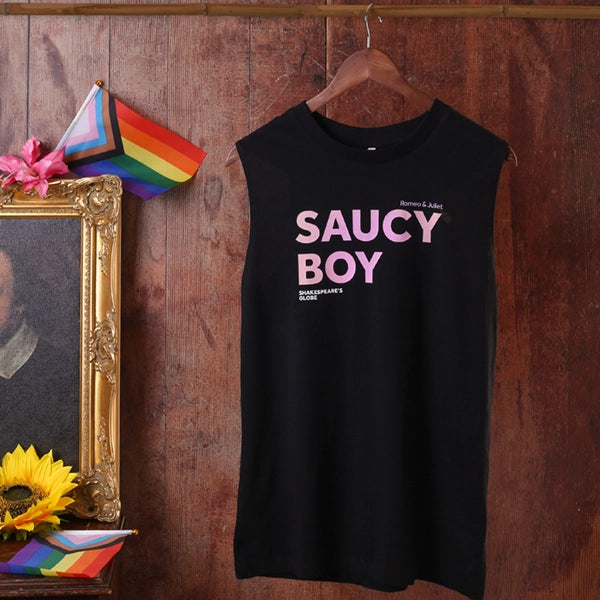 Black sleeveless shirt with 'SAUCY BOY' text on a wooden hanger against a rustic wooden wall.
