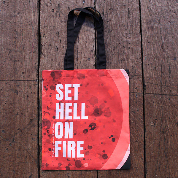 Red tote bag with all over bubbling fire graphic and block white text, with 2 black handles