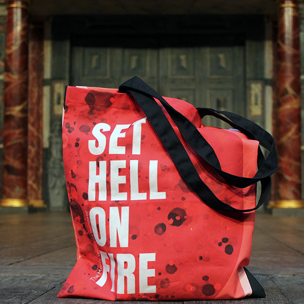 
                  
                    Red tote bag with all over bubbling fire graphic and block white text, with 2 black handles
                  
                