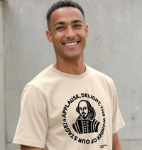 Man wearing a beige t-shirt with a graphic and text, standing against a plain background