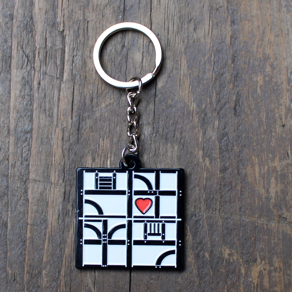 White metal key chain with a black pattern representing a half-timbered building with a red heart