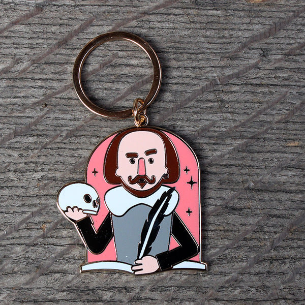 Metal cartoon Shakespeare keyring in pink, white, grey and black, featuring skull and quill