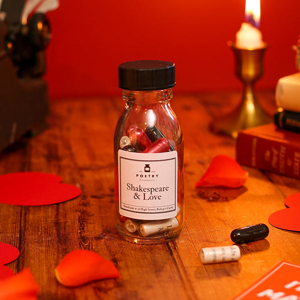 Bottle labeled 'Shakespeare & Love' on a wooden table with red hearts and a candle in the background.