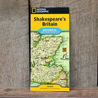 National Geographic Shakespeare's Britain folded map book standing upright against a rustic wooden plank background.