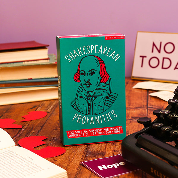 Book titled 'Shakespearean Profanities' on a wooden surface with books and a typewriter in the background.