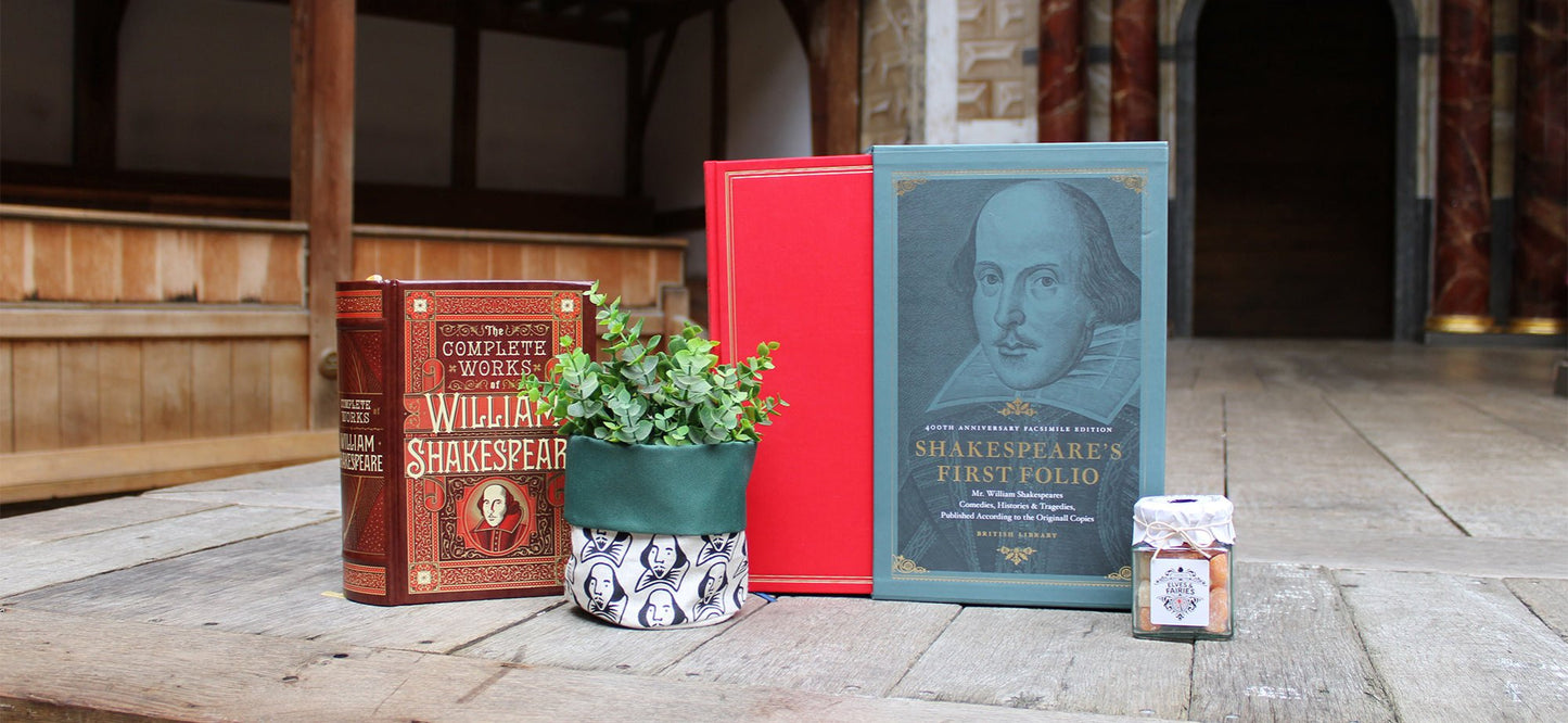 From left to right, brown leatherbound book, black, white, and green printed cloth plant pot, red and blue hardback book, glass jar of sweets on wood stage