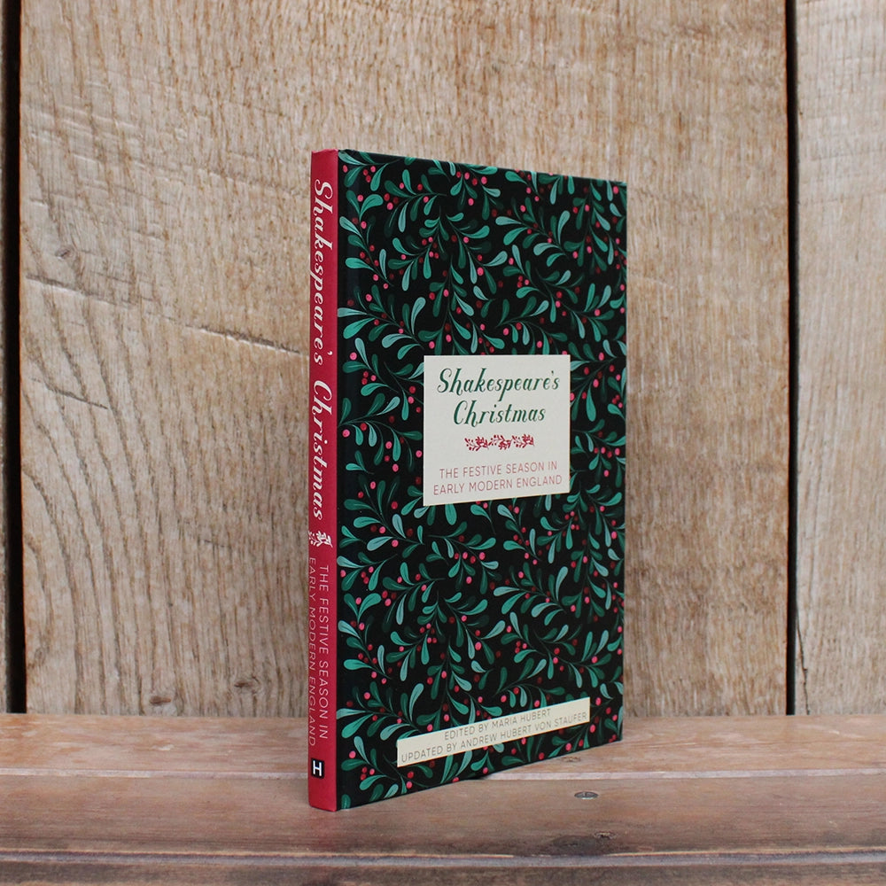 
                  
                    Hardback book with printed festive greenery and berries graphic all over, with white text box and green and red text, with red spine visible
                  
                