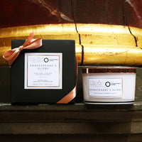 Candle and packaging with 'Shakespeare's Globe' branding on a wooden surface.