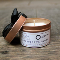 Candle in a 'Shakespeare's Globe' container on a wooden surface