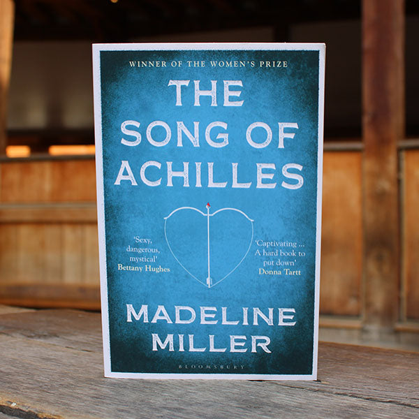 Book cover of 'The Song of Achilles' by Madeline Miller on a wooden surface.