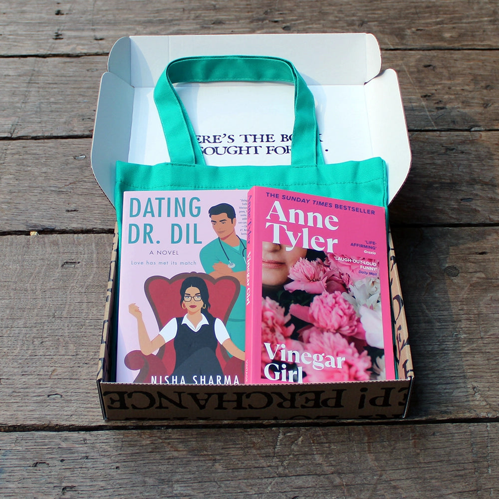 Kraft book box with white interior and exterior printed with black block text, open with teal printed bag and 2 pink books laying on top of the bag