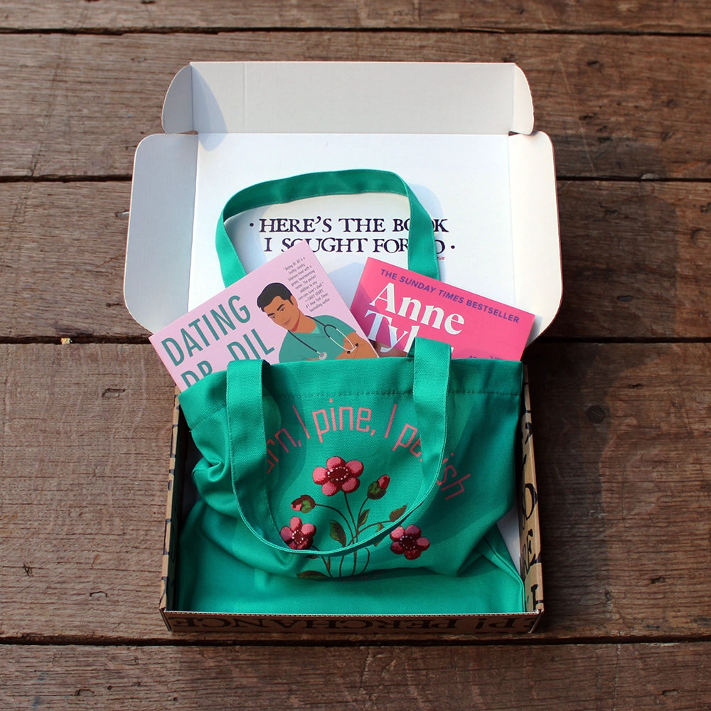 
                  
                    Kraft book box with white interior and exterior printed with black block text, open with teal printed bag and 2 pink books popping out of the top of the bag
                  
                