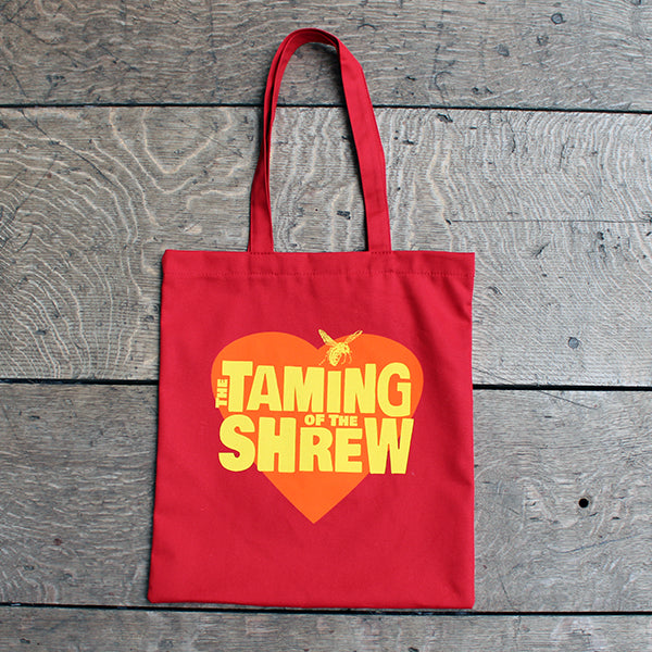 Red cotton tote bag with two handles and orange heart graphic in centre with yellow stylised text and wasp graphic