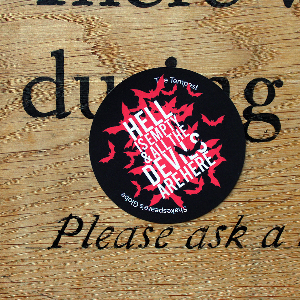 Black circular sticker with red bats graphic, overlayed with white text, stuck on wood