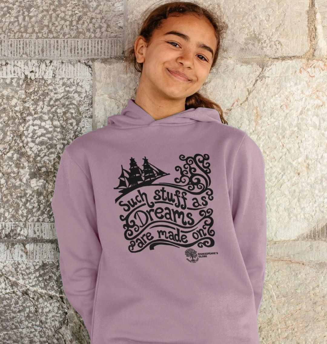 Person wearing a purple hoodie with a graphic design and text against a stone wall.