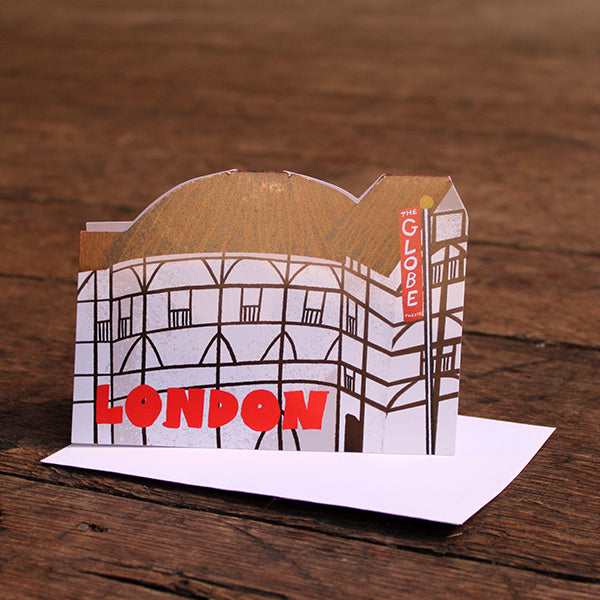 Paper greeting card shaped like the Globe Theatre, with red text and white envelope on wooden panelling