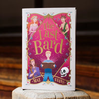 Book titled 'The Last Bard' by Maz Evans on a wooden surface with a blurred background