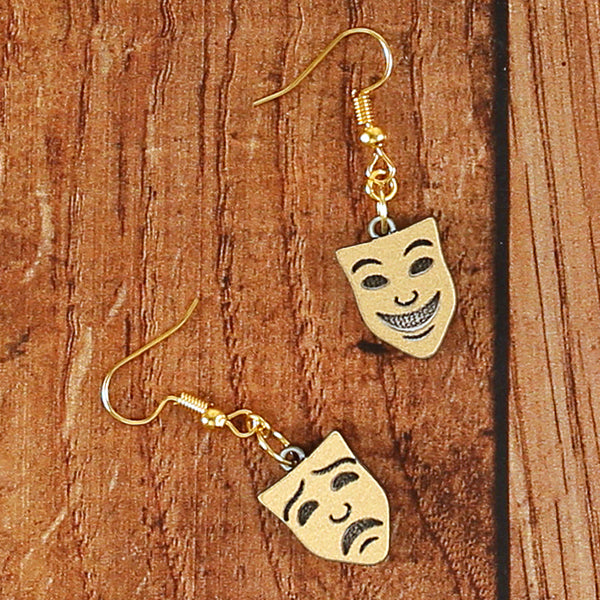 
                  
                    Gold resin mask earrings, comedy and tragedy faces sitting on wooden background
                  
                