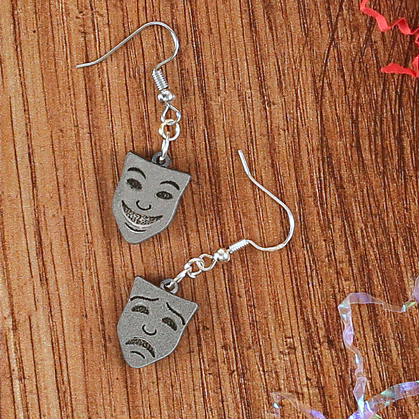 
                  
                    Silver resin mask earrings, comedy and tragedy faces sitting on wooden background
                  
                