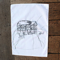 white tea towel with a black line drawing print on a wooden surface