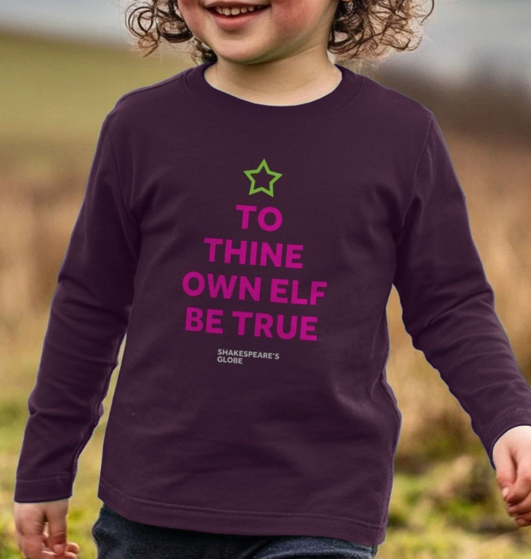 Pink graphic text in the shape of a Christmas tree with a green star on top, printed on a plum purple long-sleeve t-shirt