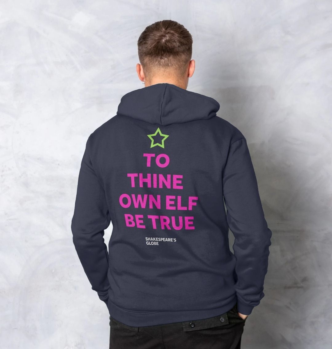 Pink graphic text in the shape of a Christmas tree with a green star on top, printed on the back of a blue adult hoodie
