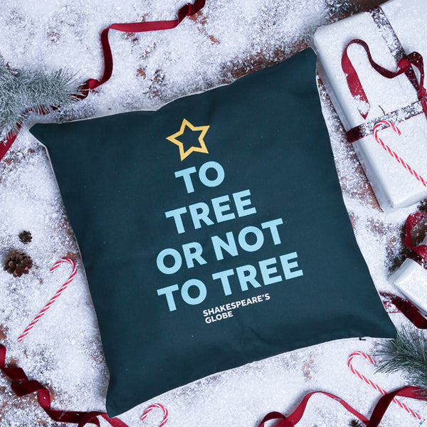 Dark green pillow with 'To Tree or Not to Tree' text and star design on a snowy background