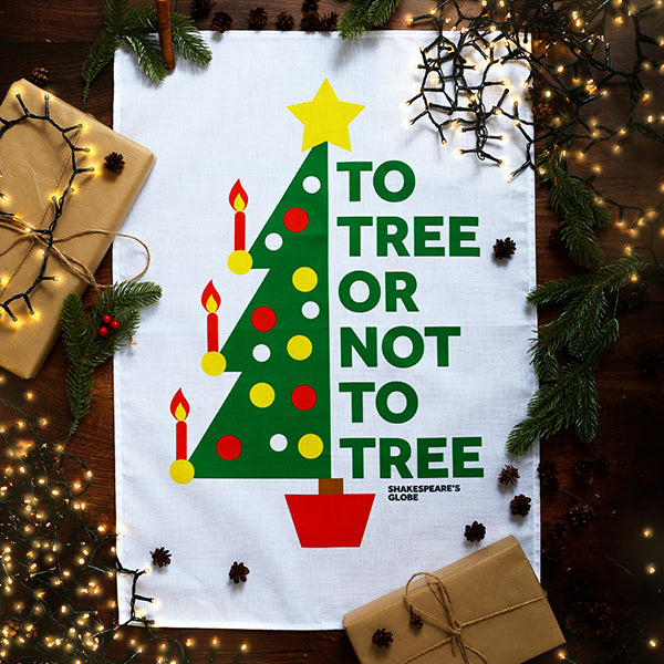 White tea towel printed with a green festive tree and a Shakespeare quote.