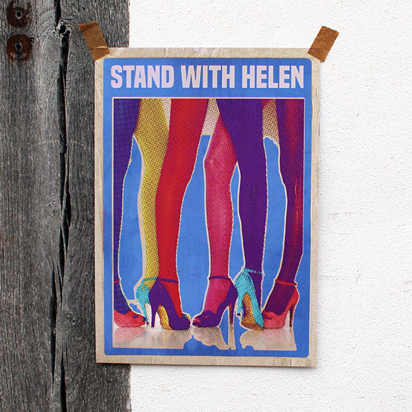 Art print with colorful legs and 'Stand With Helen' text on a wooden frame against a white wall.
