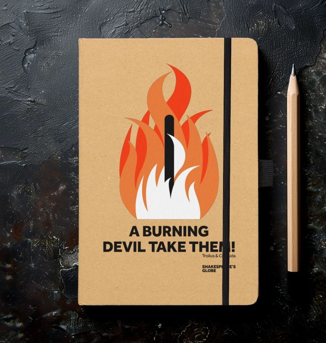 a notebook with a kraft paper cover and a print of a bonfire in orange and  red with a quote in lack beneath.