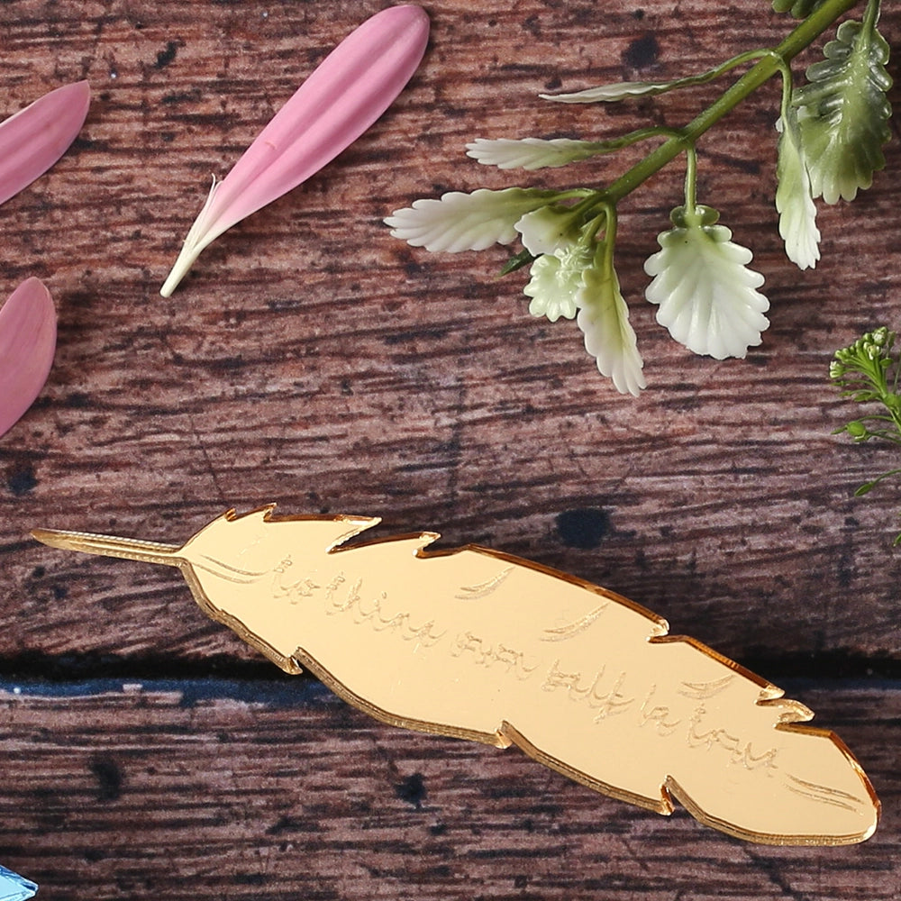 Gold mirrored acrylic brooch in the shape of a feather quill, engraved with a quote from Hamlet