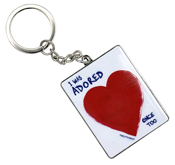 White rectangular keyring on silver metal backing, with red heart and blue text