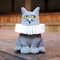 Gray cat-shaped plush toy with a white collar on a wooden surface