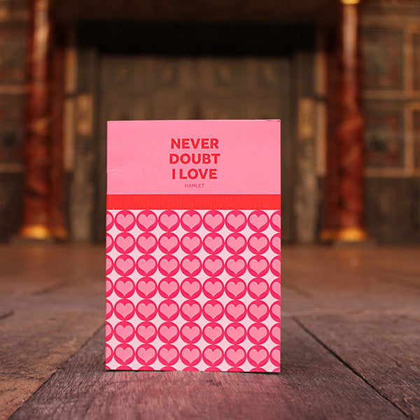 Paperback small notebook in pinks, reds, and white, with graphic text and hearts