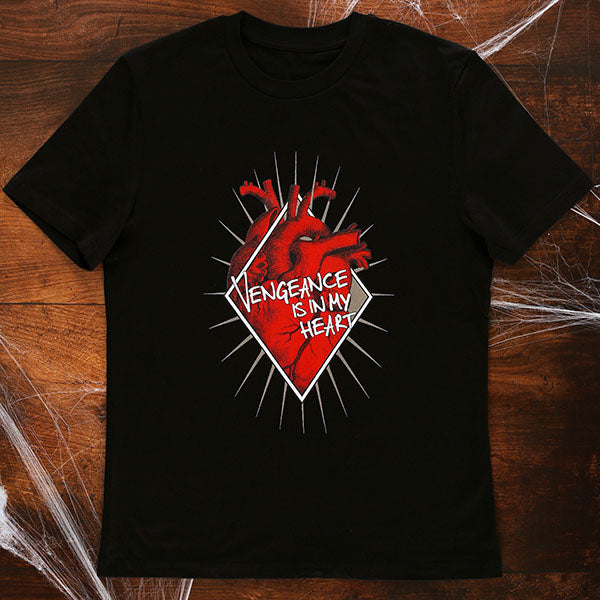 Black short sleeve, round neck cotton t-shirt with a large chest print celebrating Shakespeare play, Titus Andronicus. A red anatomical heart is partly enclosed in a white diamond shaped frame. A gold sunburst is behind the frame so that the rays are visible. Across the front of the design is a quote from the play (vengeance is in my heart) in white lettering