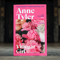 Book cover of 'Vinegar Girl' by Anne Tyler with pink flowers and a blurred background