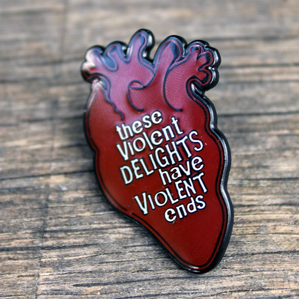 Red heart pin badge with black outline and white graphic text