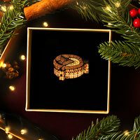 Decorative walnut brooch in a gift box surrounded by Christmas decorations on a dark background