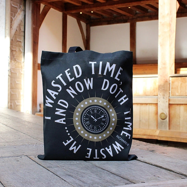 Grey cotton tote bag with two darker grey handles and gold clock with white circular text surrounding