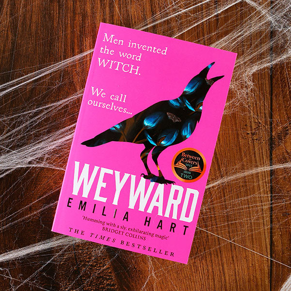Hot pink paperback book with image of a crow that appears made of flowers