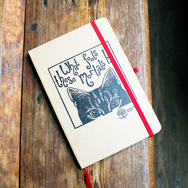 Notebook with a cat illustration and text on a wooden surface