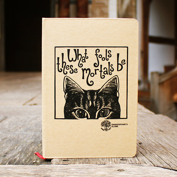 Notebook with a cat illustration and text on a wooden surface