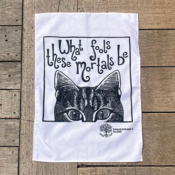 Tea tea towel with a cat illustration and text on a wooden surface