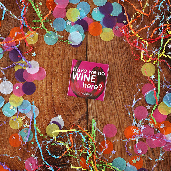 
                  
                    Pink square magnet with red swirl in background and white text quote ' Have we no wine' on wooden background with paper confetti
                  
                