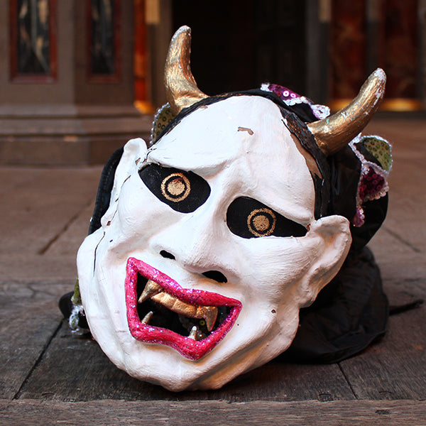 Devil-like mask with horns on a wooden surface