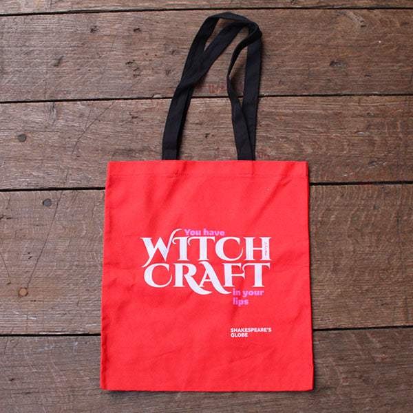 Red tote bag with 'Witch Craft' text on a wooden surface