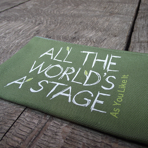 
                      
                        Sage green cotton zipped purse with a quote from Shakespeare play, As You Like It (all the world's a stage) printed in white. The lettering is hand-drawn in a scribbled style and several of the letters have little lime green leaves 'growing' from them. The title of the play is printed in lime green up the right hand side of the quote.
                      
                    