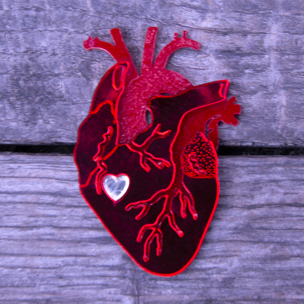 Red mirrored perspex brooch in the shape of an anatomical heart.