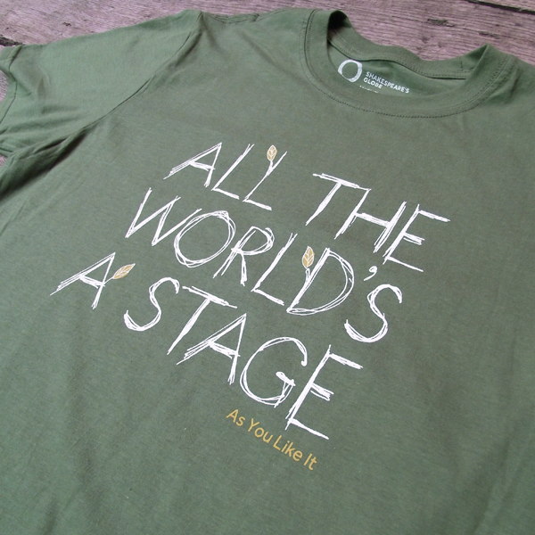 Sage green t-shirt with a round neckline. The t-shirt has a quote from Shakespeare play, As You Like It (all the world's a stage) printed in white centrally on the chest. The lettering is hand-drawn in a scribbled style to represent woodgrain and several of the lettering have lime green leaves growing out of them. The title of the play is printed in lime green under the quote.