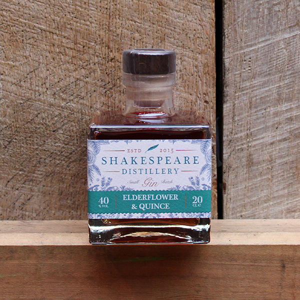 Square glass bottle with a dark coloured stopper sitting on a wooden shelf